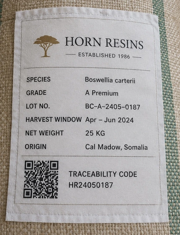 Horn Resins traceability label sewn to a jute sack, showing Boswellia carterii, Grade A Premium, lot BC-A-2405-0187, harvest window April to June 2024, 25 kg net and origin Cal Madow, Somalia, with a QR traceability code
